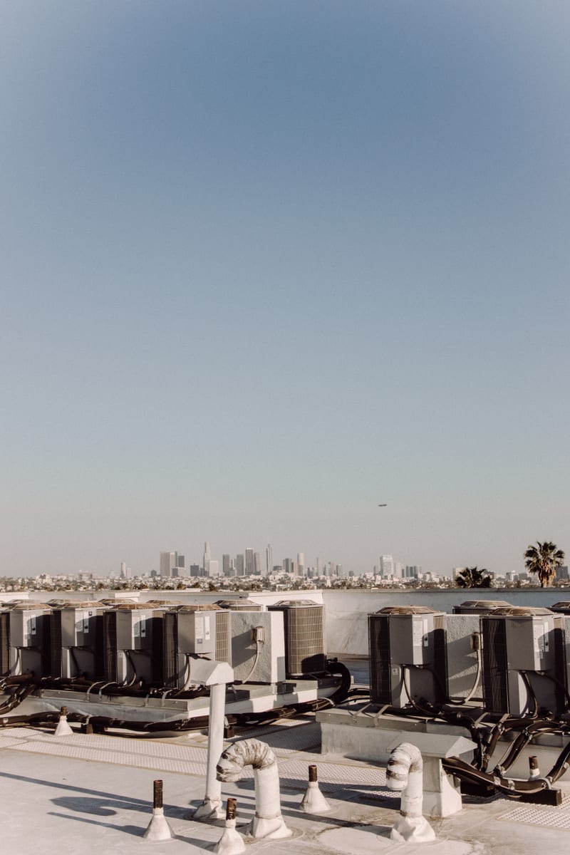 Low-slope commercial membrane roof with HVAC curbs, pipe penetrations, and service paths